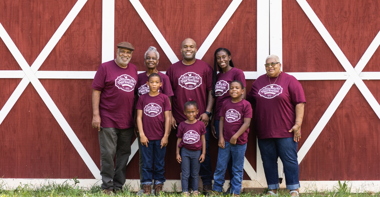 A family of eight pose in front of a red barn on their property in Georgia