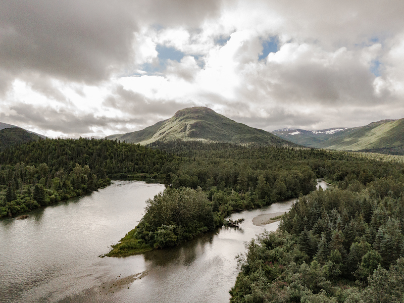 River with trees with hills in the background and white clouds