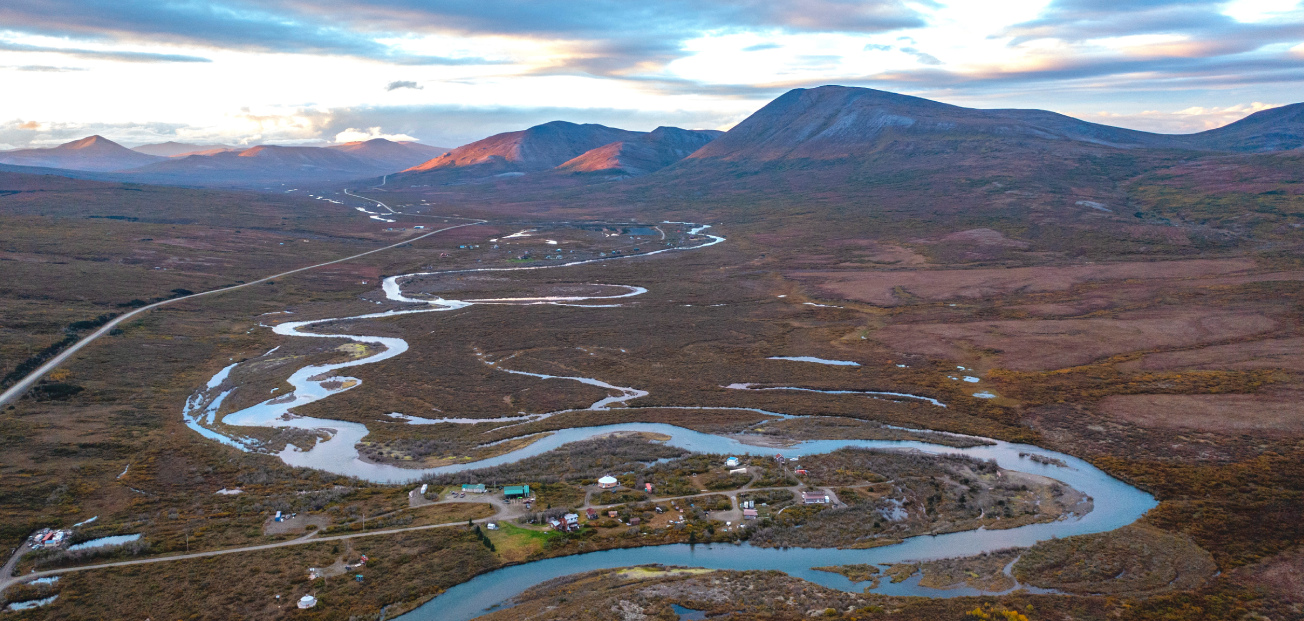A river flows through a valley in Nome, Alaska, surrounded by mountains, highlighting a protected wildlife habitat.