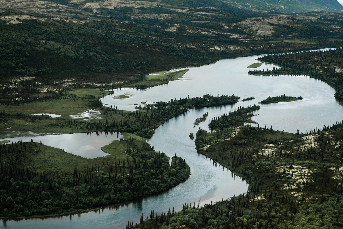 Winding river with trees on either side and hills rising on the left side