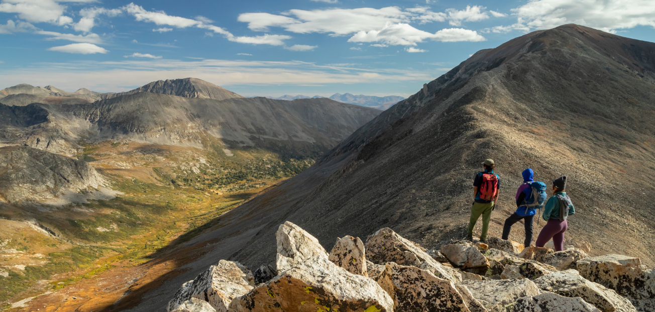 Three people overlooking a mountain landscape
