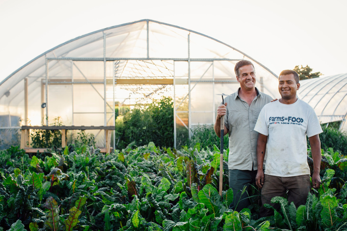 Rustic Road Farm's owners stand among produce growing on their farm.