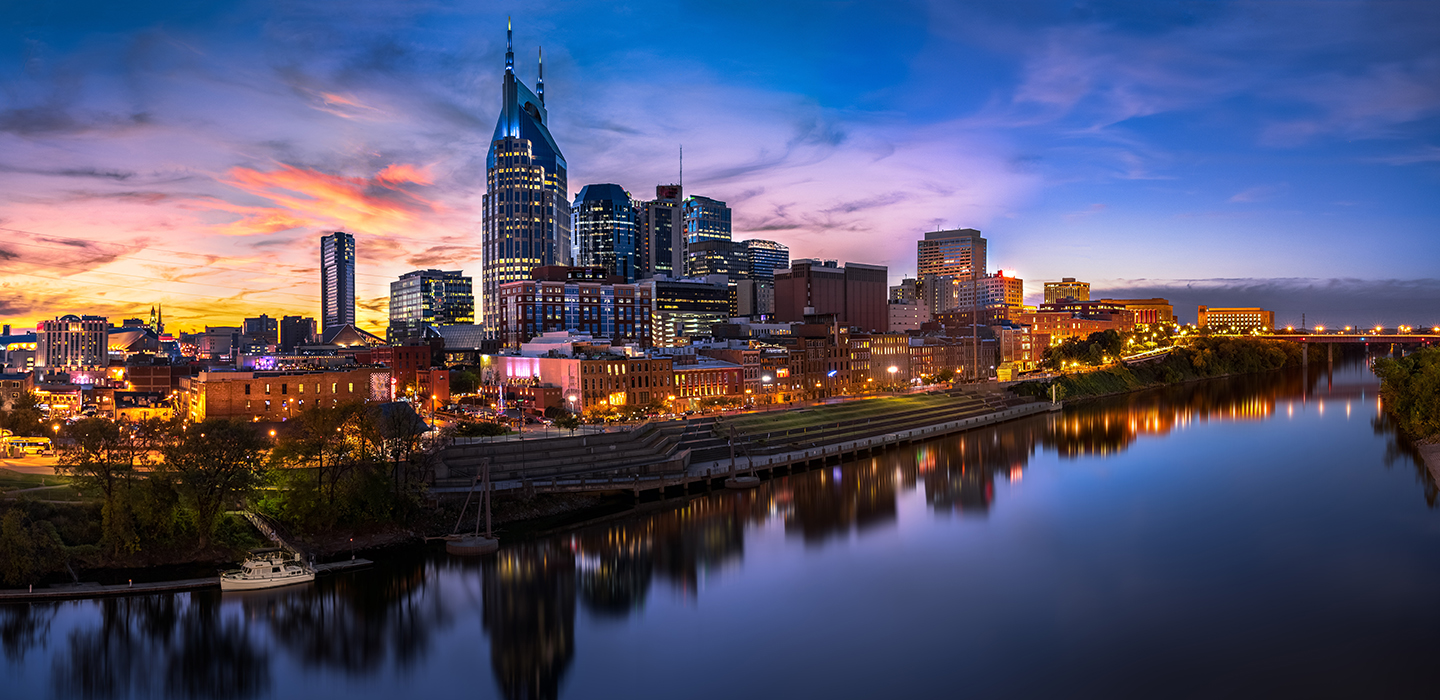 The Nashville skyline along the river with a colorful, cloudy sunset