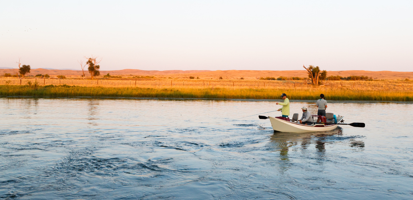 Three men fish in a small board on the water at Marton Ranch