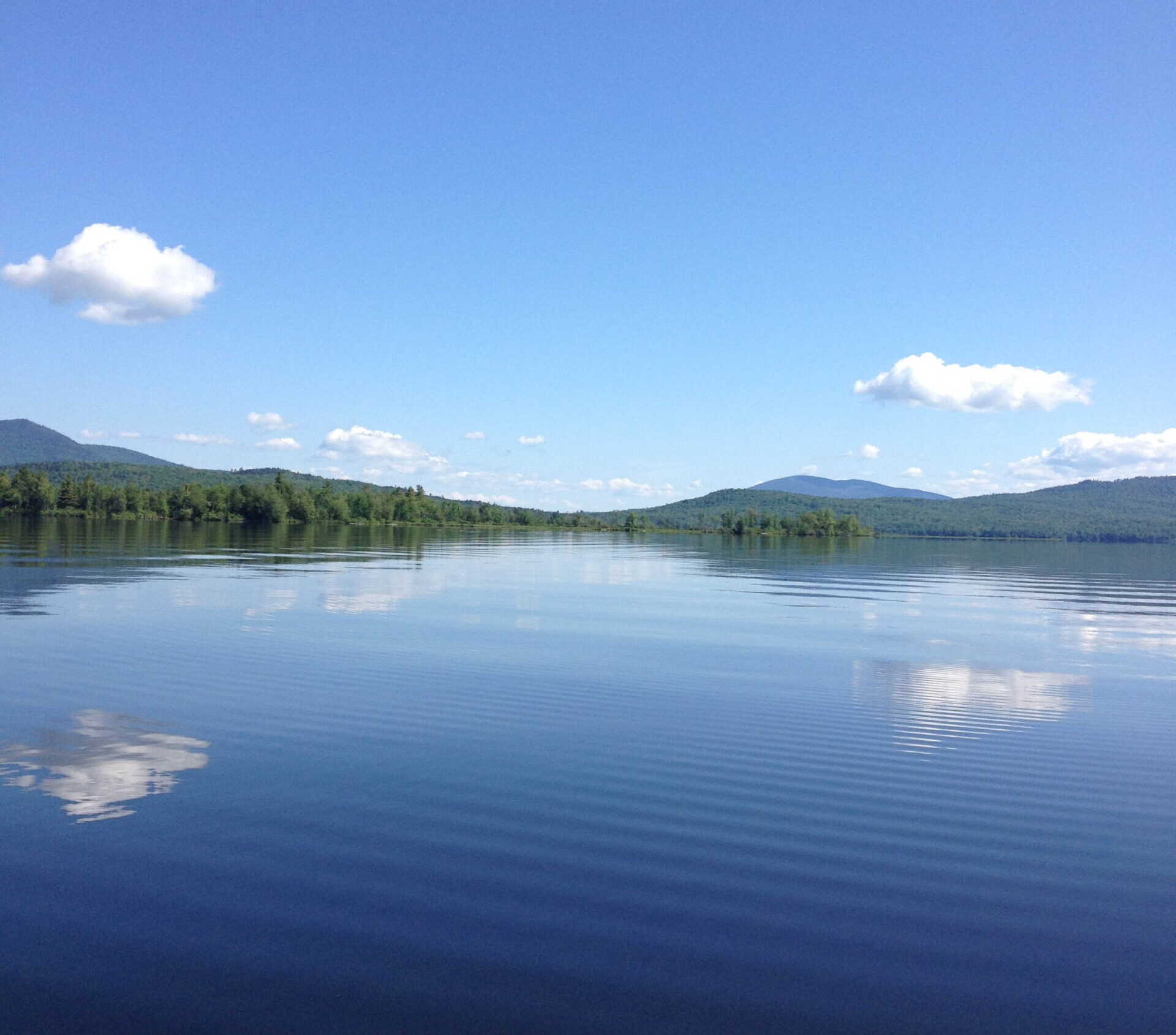 An image on a very blue Lake Umbagog, Maine with trees in the background