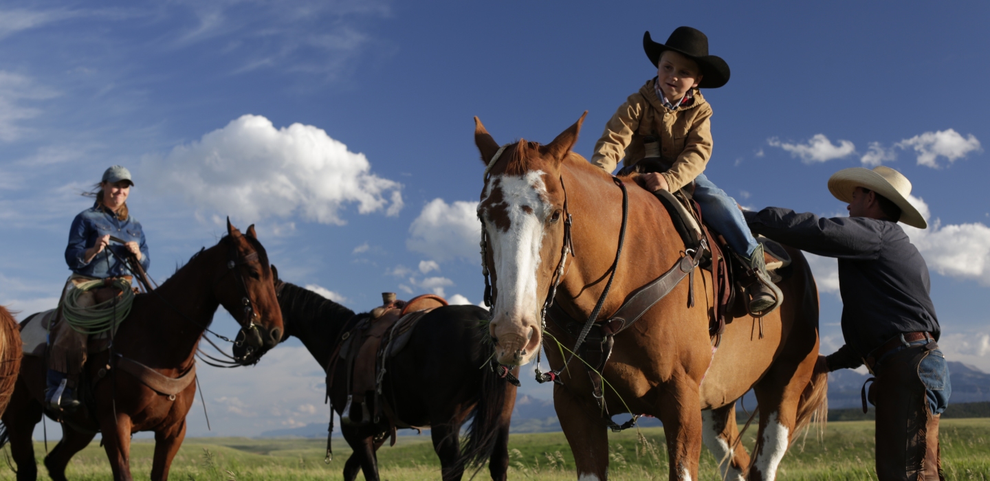 A family with a young boy are seen getting ready to ride three horses on a Crabb Ranch