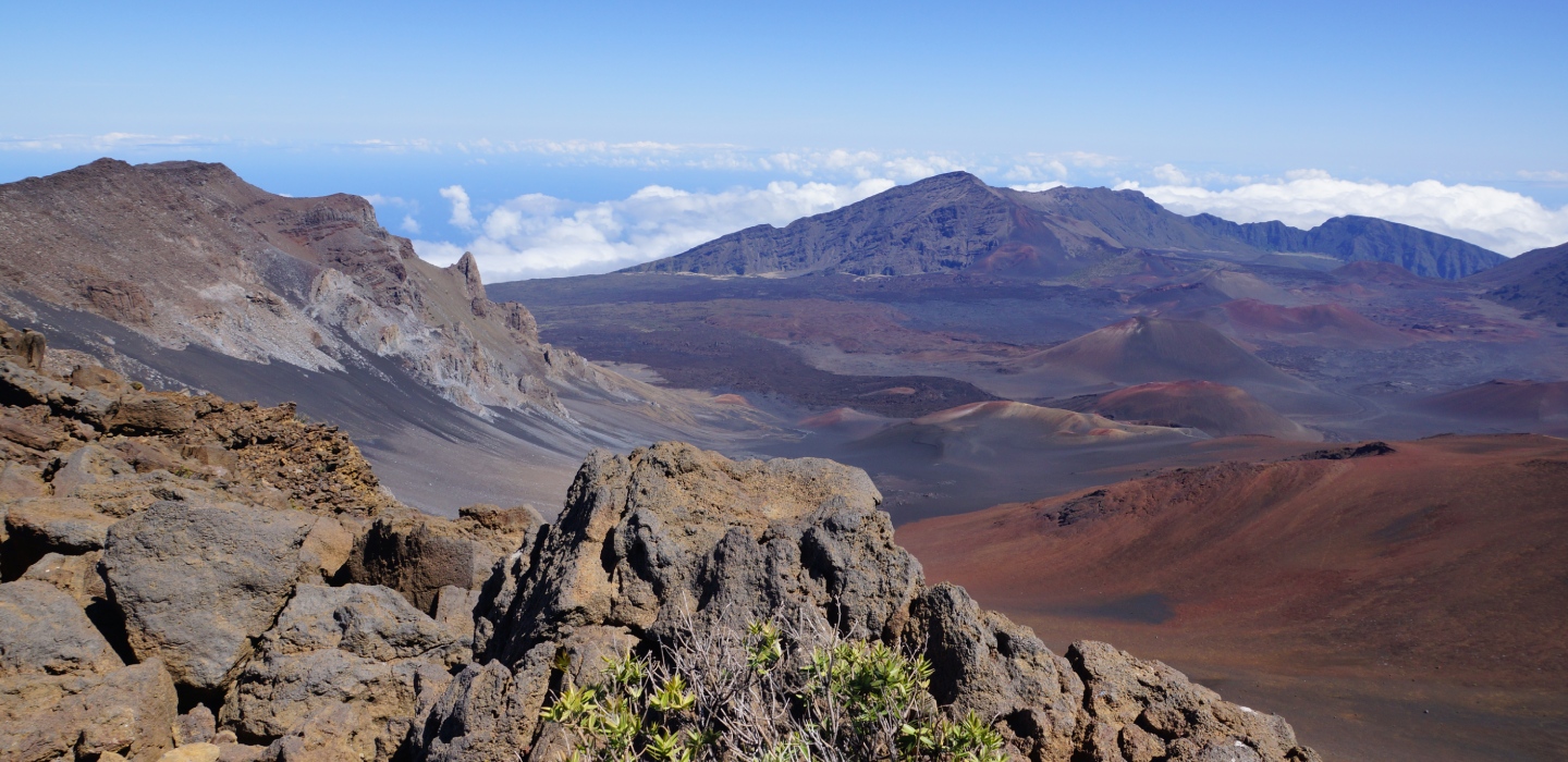 Large rocks adorn a hillside with mountains in the background on a cloudy day at Haleakalā National Park