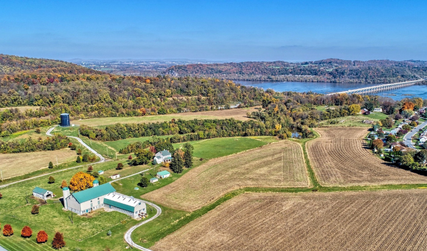 Mifflin House shows itself in the foreground with fall trees and a river running under a bridge in the background