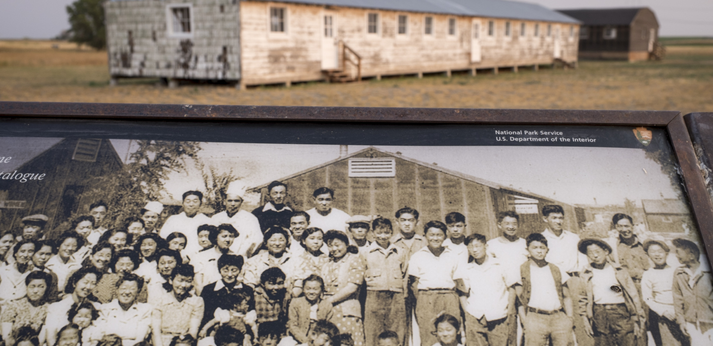 An informative plaque in the foreground with barracks in the background at Minidoka National Historic Site
