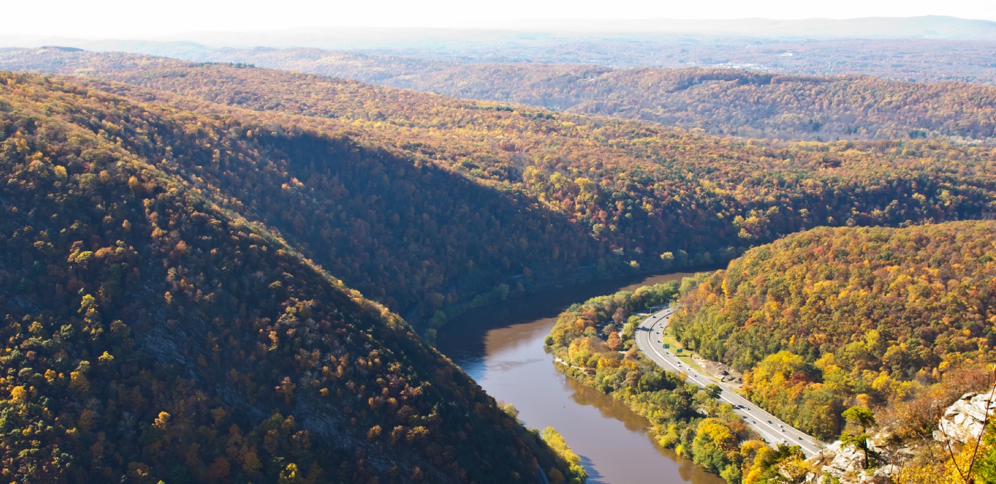 An aerial image of the Delaware Water Gap National Recreation Area with a road running next to a river at the basin of small rolling hills