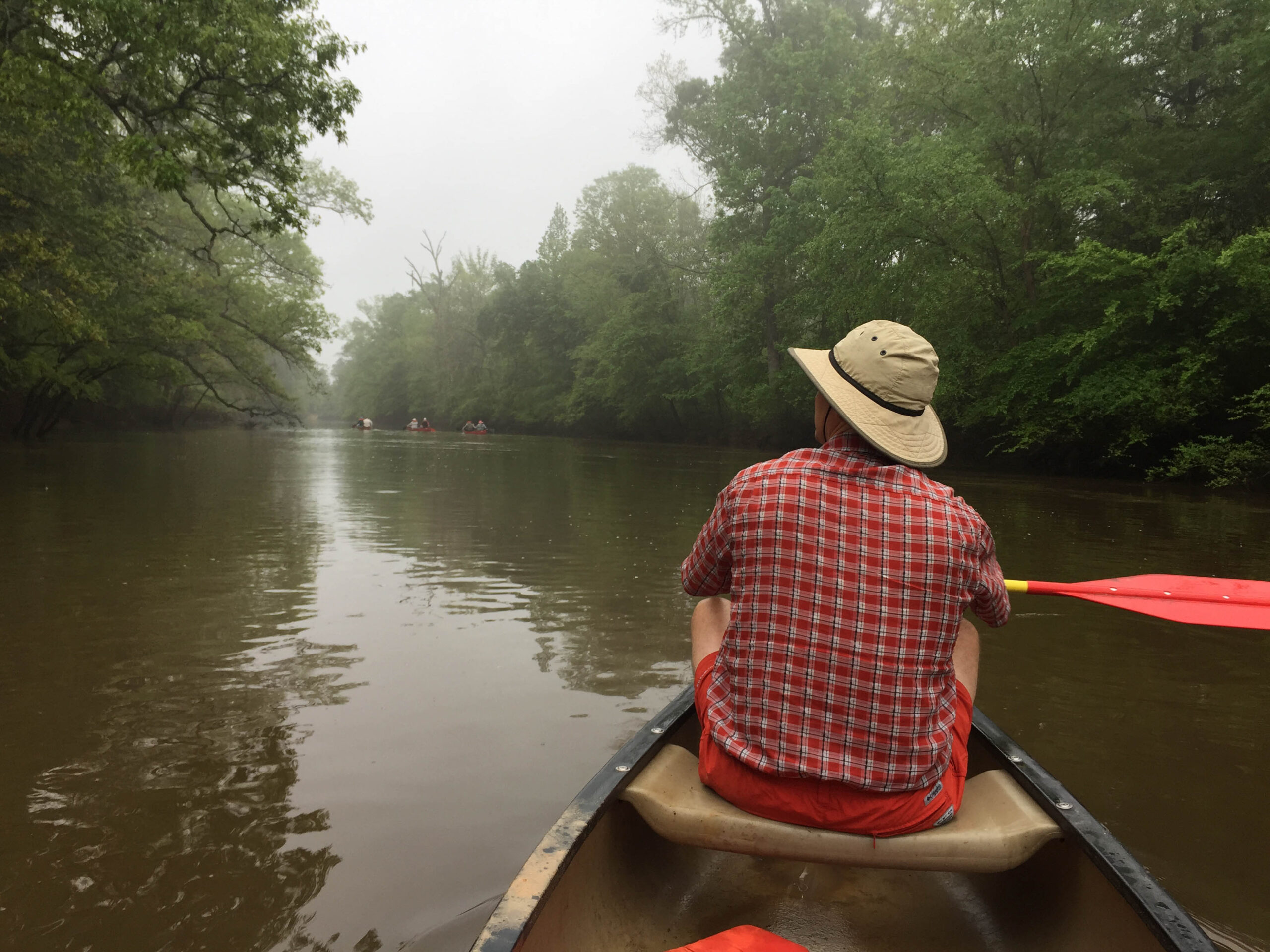 The back of a man canoeing the Neches River in Texas
