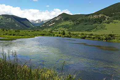Bouler Creek flows in Colorado. Green mountains linger in the background.