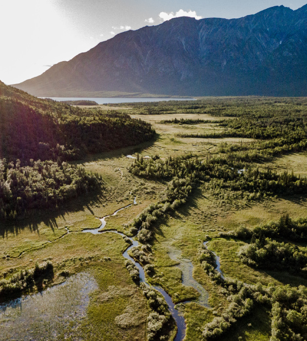 Aerial view of Eklutna River winding through mountains in Alaska, showcasing the natural beauty of the landscape.