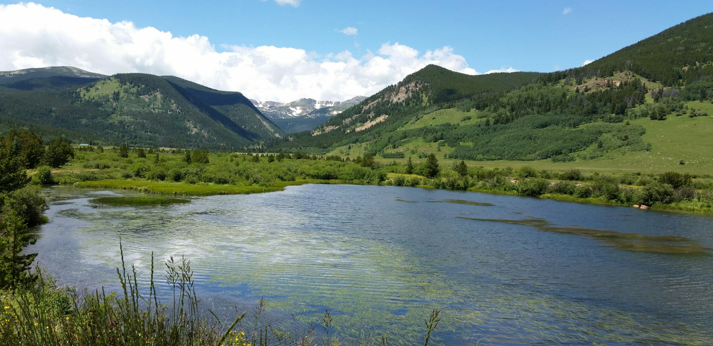 Tolland Ranch is nestled in a valley where a river winds through, bordered by majestic mountains.
